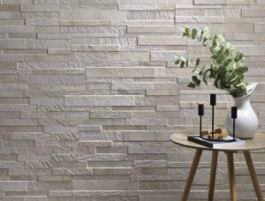 Modern interior featuring a textured stone wall with a plant and decorative items on a table.